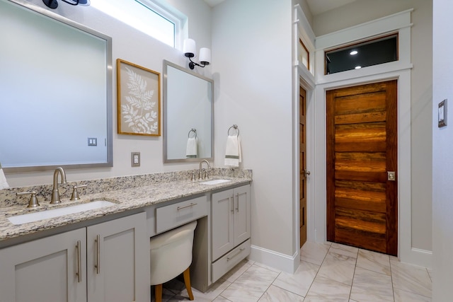 bathroom featuring baseboards, marble finish floor, a sink, and double vanity