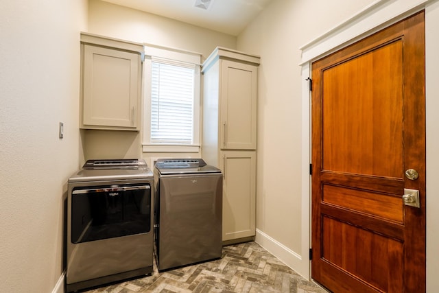 laundry area featuring washing machine and clothes dryer, brick floor, baseboards, and cabinet space