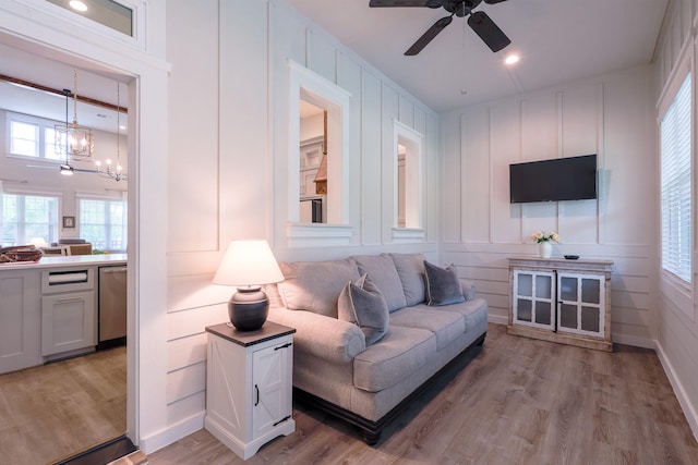 living area featuring light wood-style floors, plenty of natural light, and a decorative wall
