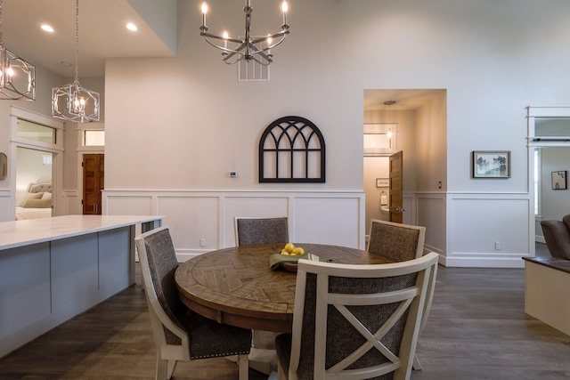 dining area with a decorative wall, a notable chandelier, and a high ceiling