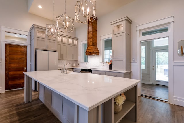 kitchen with dark wood-style floors, a kitchen island, light stone countertops, a chandelier, and tasteful backsplash