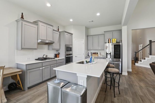 3651 Rainwater Trl, Grand Prairie, TX 76065 - kitchen featuring gray cabinetry, a sink, stainless steel appliances, under cabinet range hood, and a kitchen breakfast bar