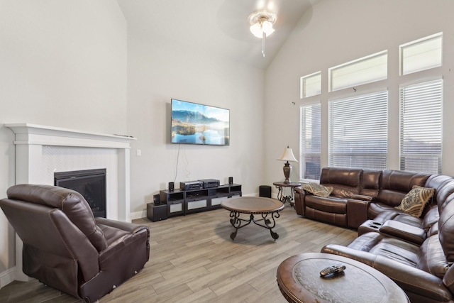 3651 Rainwater Trl, Grand Prairie, TX 76065 - living area with light wood-type flooring, ceiling fan, high vaulted ceiling, a glass covered fireplace, and baseboards