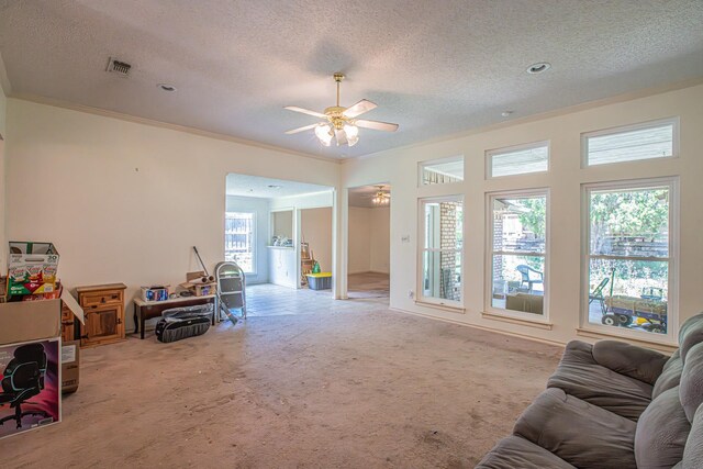 carpeted living area featuring a textured ceiling, crown molding, ceiling fan, and visible vents