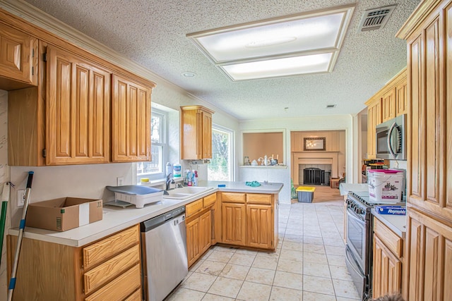 kitchen with a peninsula, a sink, visible vents, light countertops, and appliances with stainless steel finishes