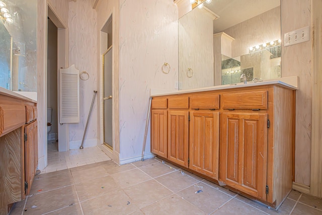 full bath with baseboards, vanity, tile patterned floors, and a stall shower