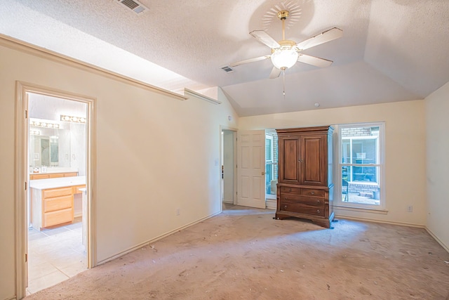 interior space featuring light carpet, lofted ceiling, a textured ceiling, and visible vents