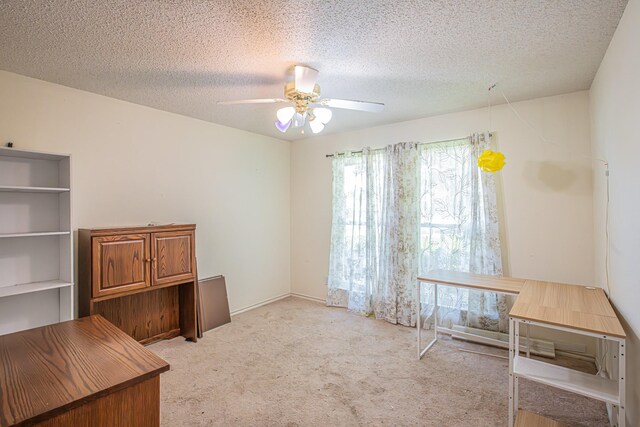 unfurnished office featuring light carpet, a textured ceiling, and ceiling fan