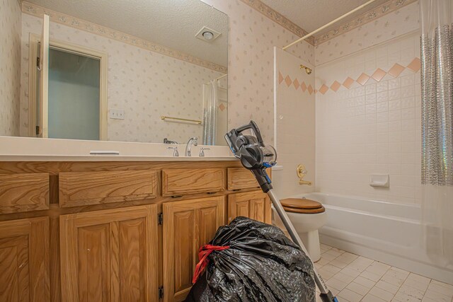 bathroom with wallpapered walls, shower / bath combination with curtain, toilet, vanity, and a textured ceiling