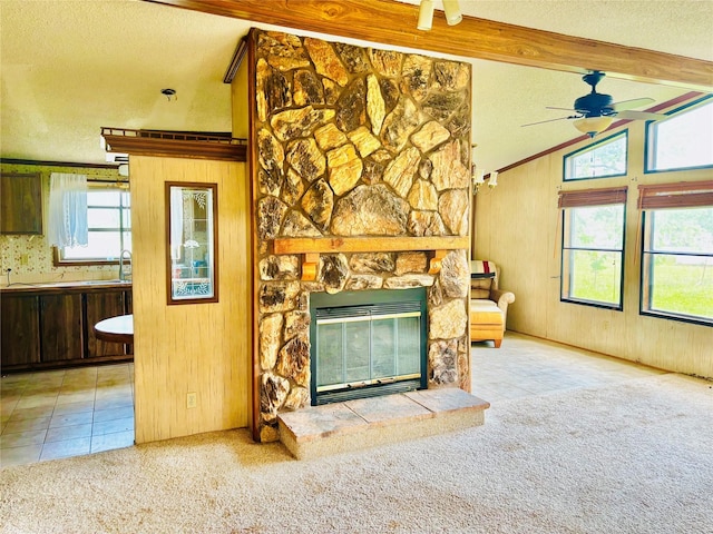 458 Jackson Ave, Strawn, TX 76475 - unfurnished living room featuring a textured ceiling, carpet floors, vaulted ceiling with beams, a ceiling fan, and a fireplace