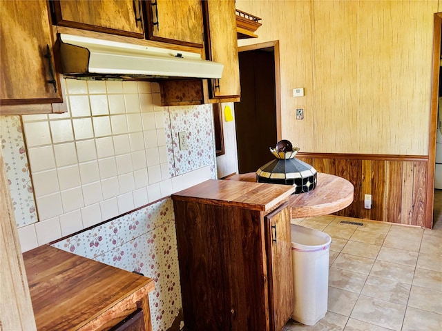 458 Jackson Ave, Strawn, TX 76475 - kitchen with visible vents, under cabinet range hood, wood walls, and light tile patterned flooring