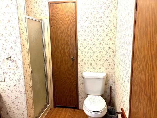 458 Jackson Ave, Strawn, TX 76475 - full bath featuring wallpapered walls, wood finished floors, toilet, and a stall shower