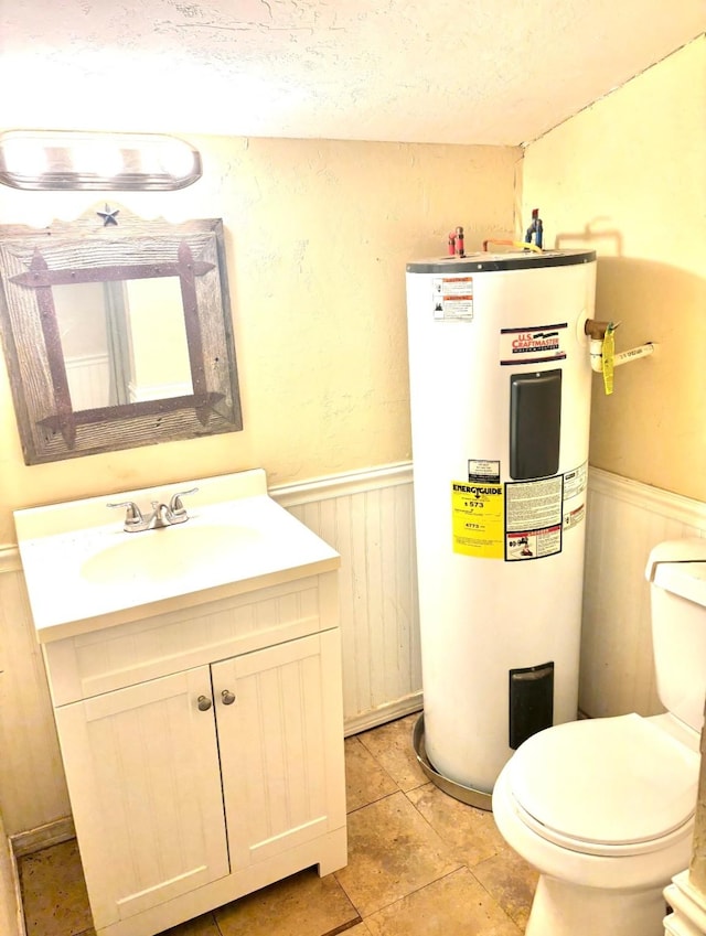 458 Jackson Ave, Strawn, TX 76475 - half bathroom featuring water heater, toilet, vanity, wainscoting, and a textured ceiling