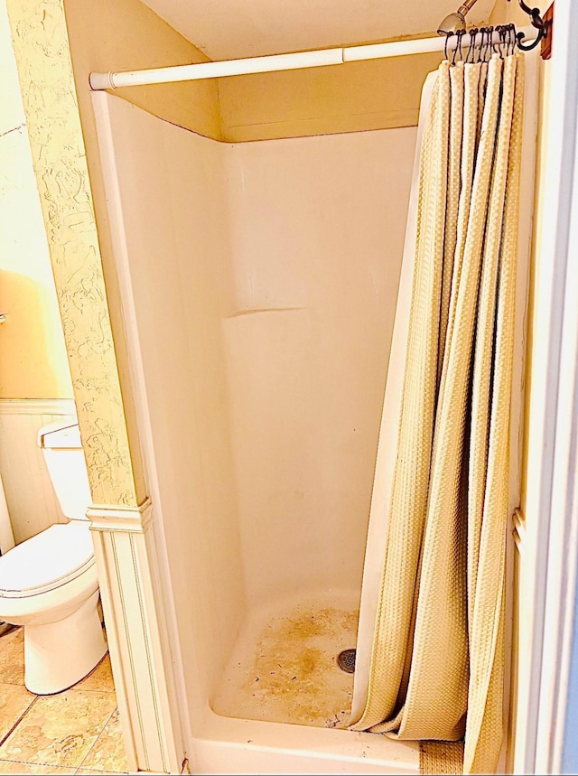 458 Jackson Ave, Strawn, TX 76475 - full bathroom featuring a shower stall, a wainscoted wall, and toilet