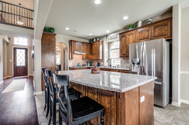 14225 Signal Hill Dr, Little Elm, TX 75068 - kitchen featuring stainless steel fridge, arched walkways, a kitchen island, a sink, and baseboards