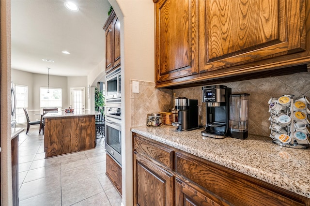 14225 Signal Hill Dr, Little Elm, TX 75068 - kitchen with appliances with stainless steel finishes, decorative backsplash, light stone counters, light tile patterned floors, and a kitchen island
