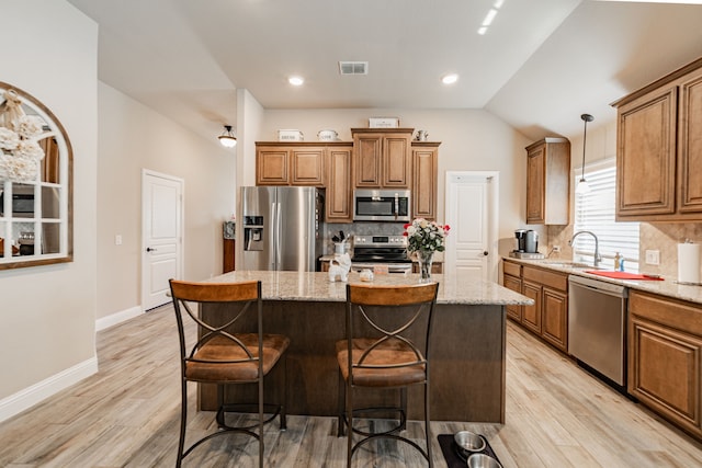 kitchen with brown cabinets, stainless steel appliances, backsplash, visible vents, and a sink