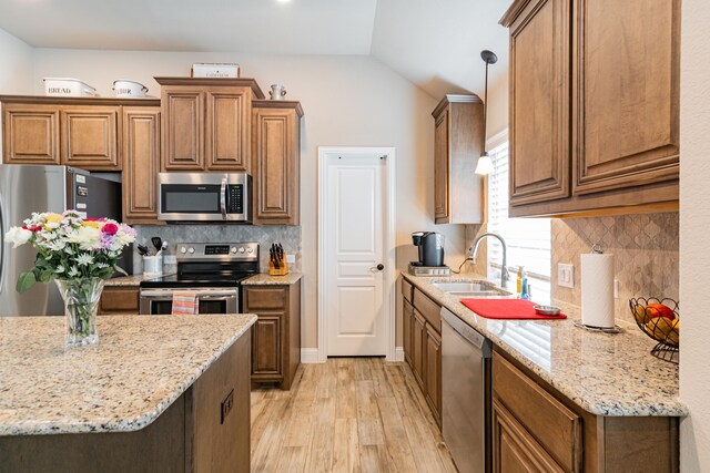 kitchen featuring light wood-type flooring, stainless steel appliances, a sink, and brown cabinetry