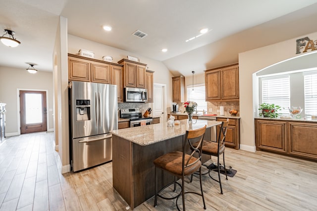 kitchen featuring visible vents, decorative backsplash, light stone countertops, brown cabinetry, and appliances with stainless steel finishes