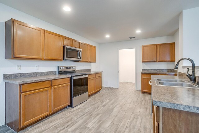 5817 Mirror Ridge Dr, Fort Worth, TX 76179 - kitchen with stainless steel appliances, light wood-type flooring, ceiling fan, open floor plan, and brown cabinetry