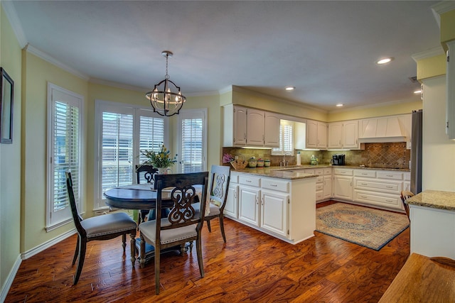 kitchen with decorative backsplash, a chandelier, white cabinets, dark wood-style floors, and freestanding refrigerator