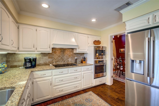 kitchen with custom exhaust hood, appliances with stainless steel finishes, light stone countertops, dark wood-type flooring, and visible vents