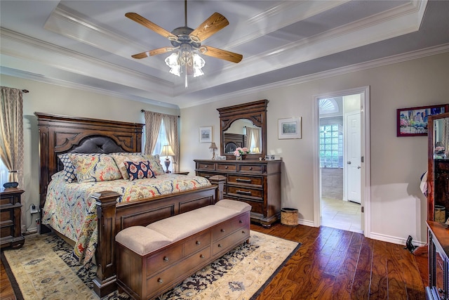 bedroom with baseboards, wood finished floors, a raised ceiling, and crown molding
