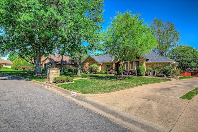 single story home with roof with shingles, stone siding, and a front yard
