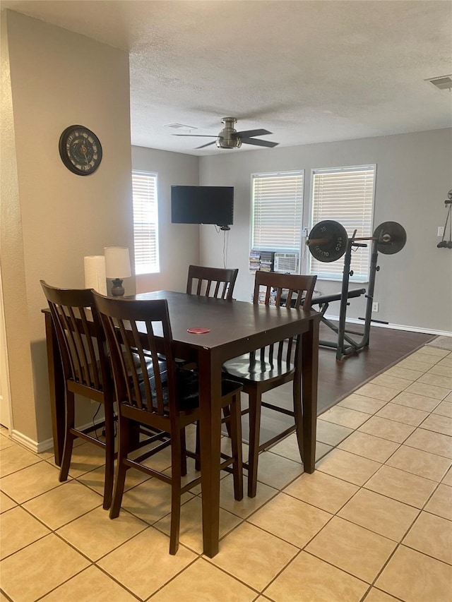 dining room featuring a ceiling fan, visible vents, light tile patterned flooring, and a textured ceiling