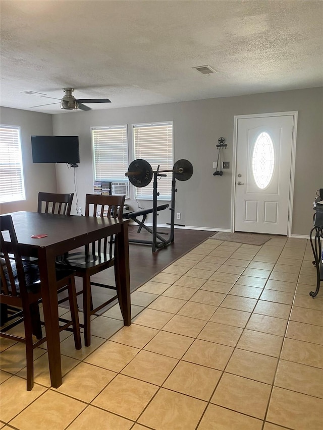 dining area featuring light tile patterned flooring, a textured ceiling, a ceiling fan, and visible vents