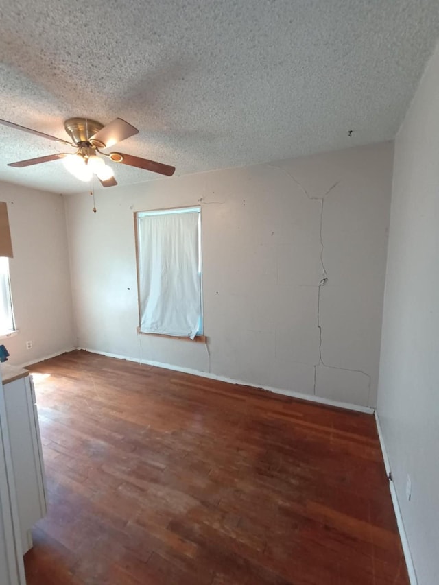 empty room with baseboards, a ceiling fan, wood finished floors, and a textured ceiling