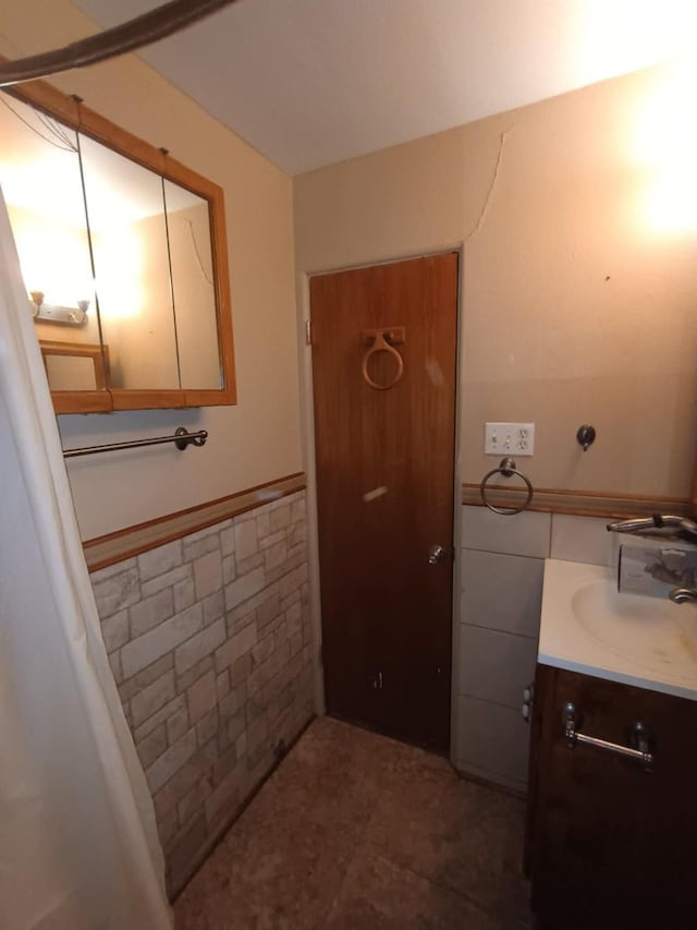 bathroom featuring tile walls, vanity, and wainscoting