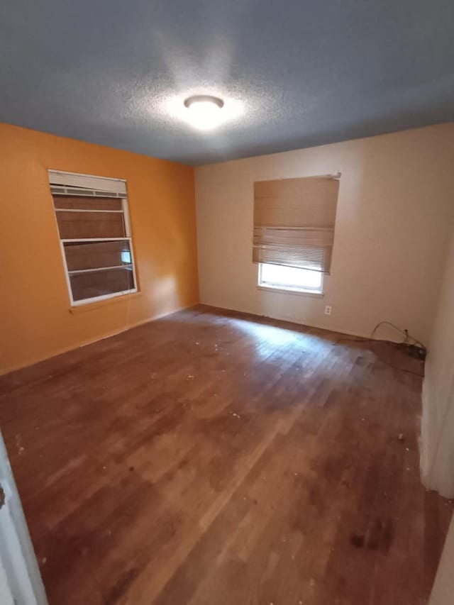 empty room featuring baseboards, wood finished floors, and a textured ceiling