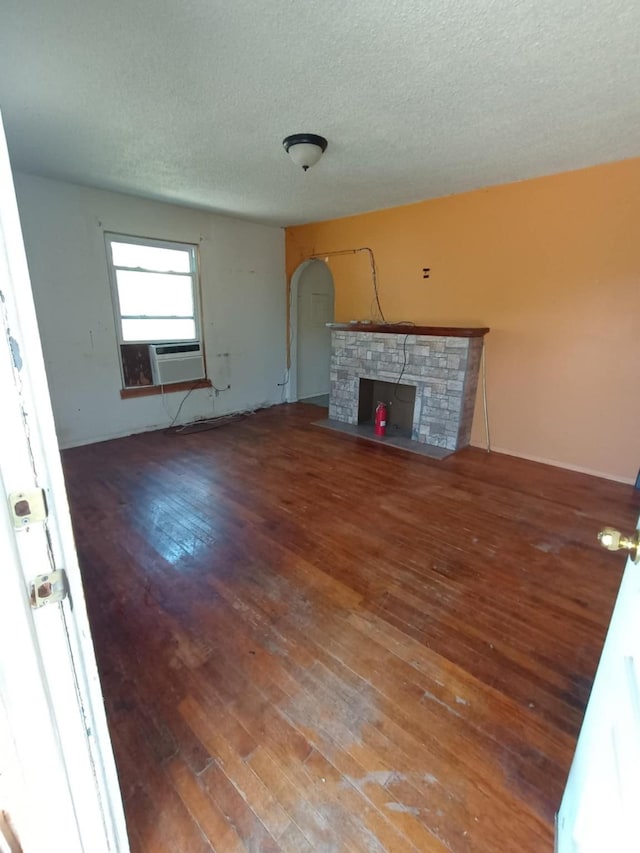 unfurnished living room featuring a fireplace with flush hearth, arched walkways, a textured ceiling, and wood-type flooring