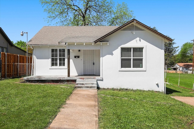 bungalow-style house featuring covered porch, a front lawn, stucco siding, and fence