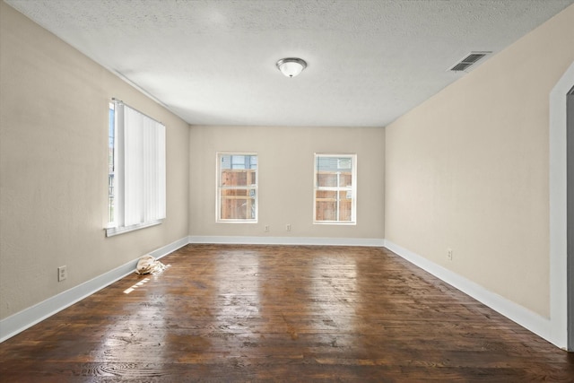 unfurnished room with visible vents, baseboards, a textured ceiling, and dark wood-style flooring