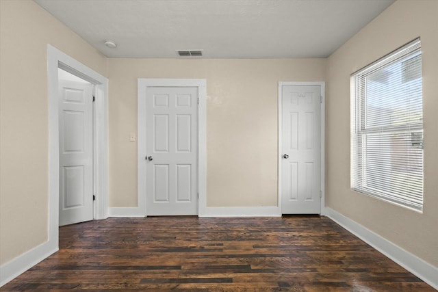 unfurnished bedroom featuring baseboards, visible vents, and dark wood-style floors