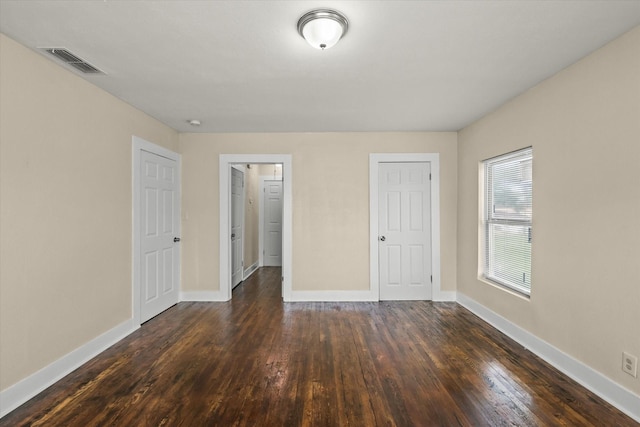 unfurnished bedroom with visible vents, baseboards, and dark wood-style flooring