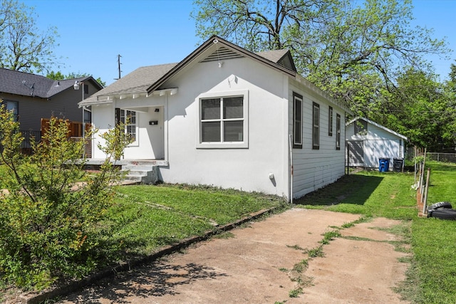 view of front facade with stucco siding, a front lawn, and fence