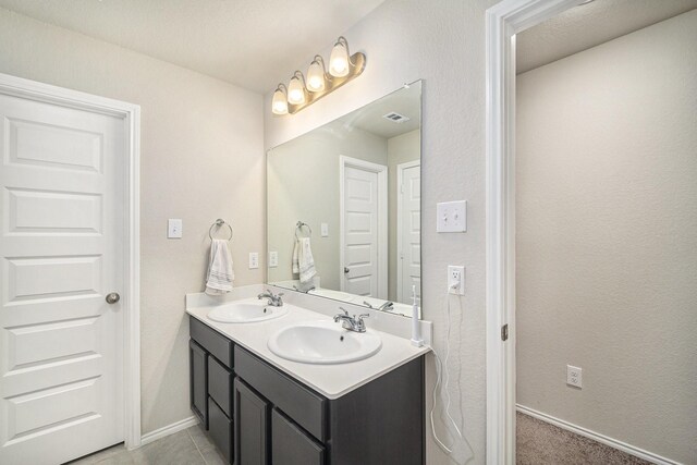 full bath featuring baseboards, visible vents, a sink, and double vanity