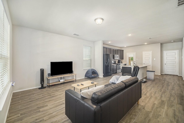 living room featuring visible vents, light wood finished floors, and baseboards