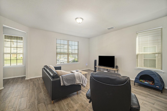 living area featuring baseboards, wood finished floors, and visible vents