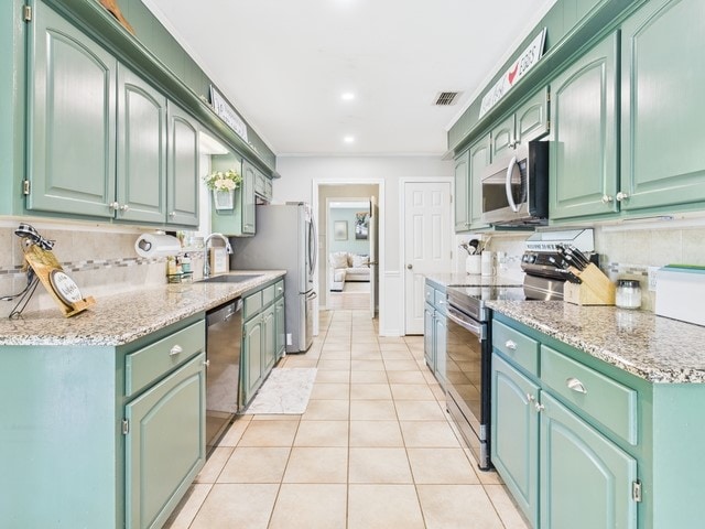 kitchen with recessed lighting, stainless steel appliances, light tile patterned floors, a sink, and light stone countertops