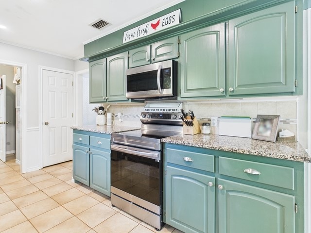 kitchen with light tile patterned flooring, appliances with stainless steel finishes, backsplash, ornamental molding, and visible vents