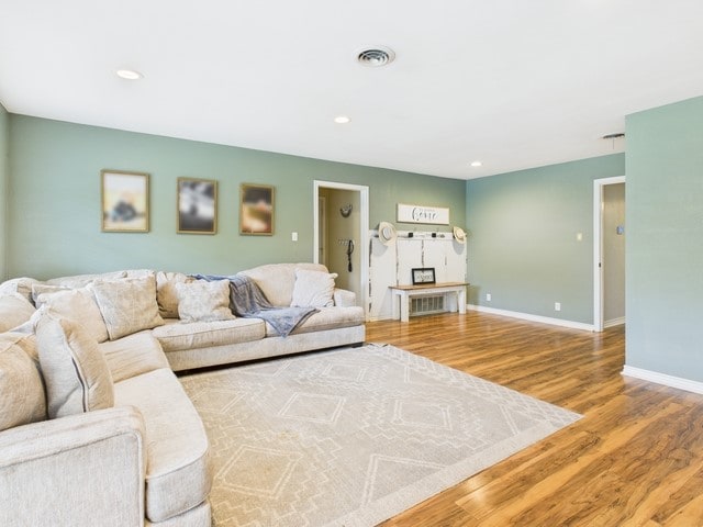 living room featuring baseboards, wood finished floors, visible vents, and recessed lighting