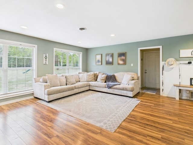 living area with baseboards, wood finished floors, visible vents, and recessed lighting