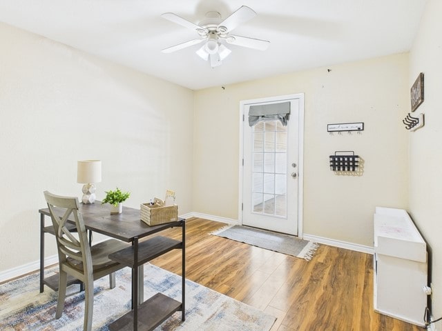 office space with baseboards, a ceiling fan, and wood finished floors