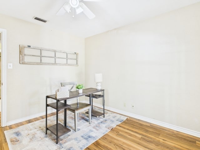 office area featuring visible vents, baseboards, wood finished floors, and ceiling fan