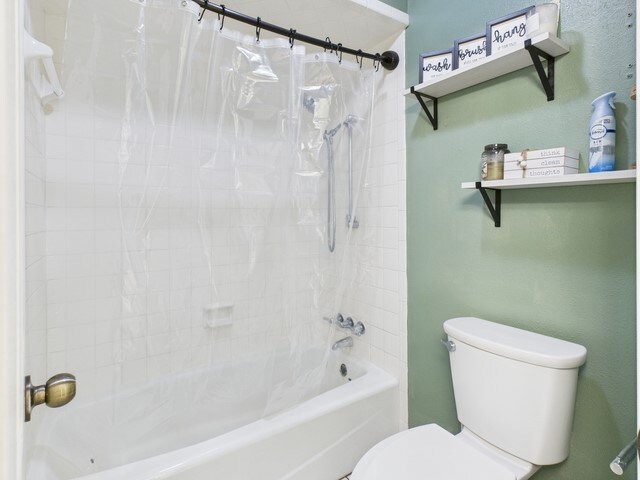 bathroom featuring shower / bath combination with curtain and toilet
