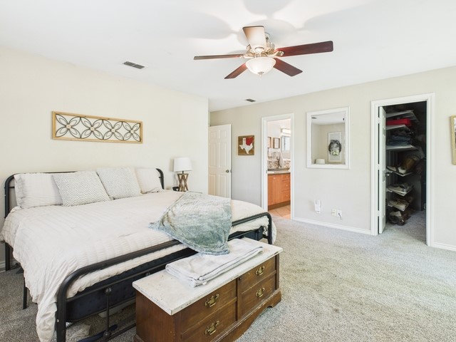 bedroom with light carpet, baseboards, visible vents, a spacious closet, and connected bathroom